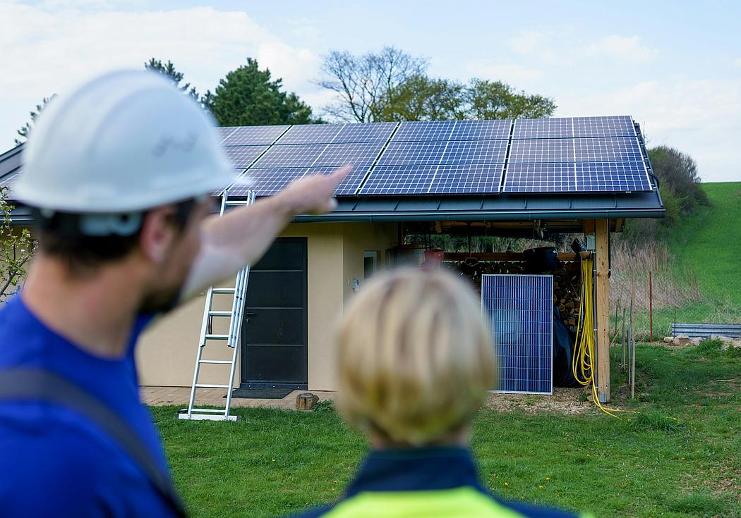 Ein Mann zeigt auf eine Solardachanlage