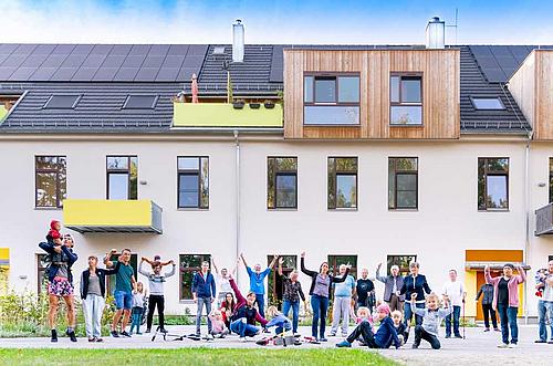 Menschen vor Mehrfamilienhaus mit Photovoltaik in Weimar