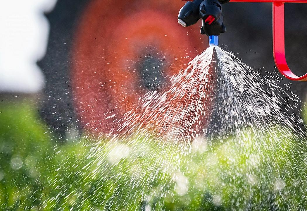 Traktor auf Feld versprüht Pestizide