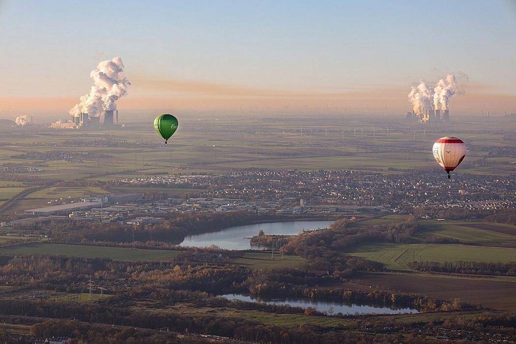 Heißluftballons über Landschaft mit Kohlekraftwerken