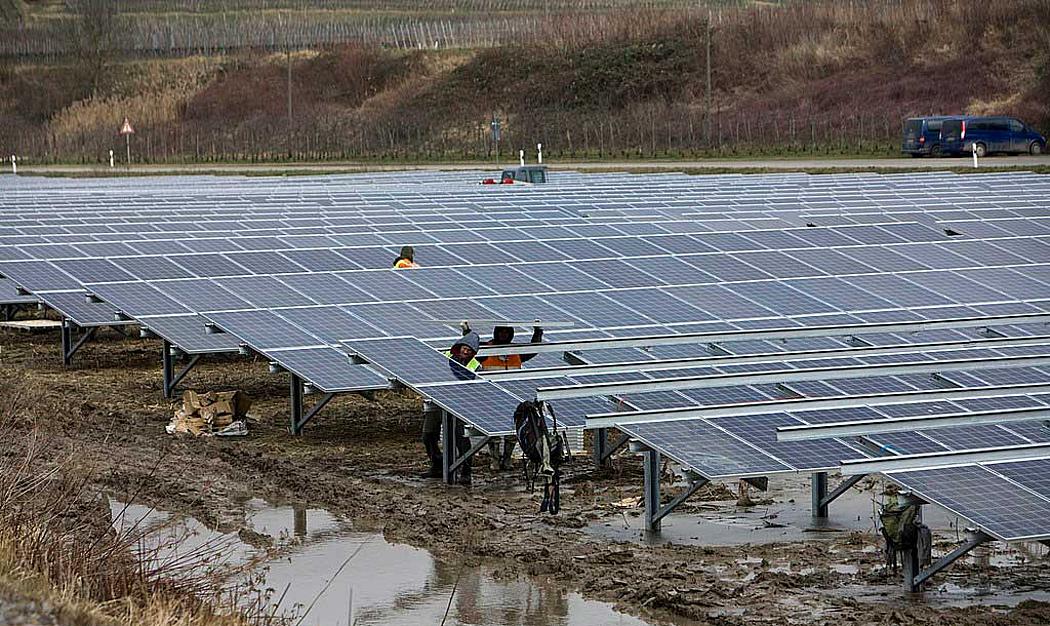 Arbeiter bei der Montage in einem Solarpark bei Regen