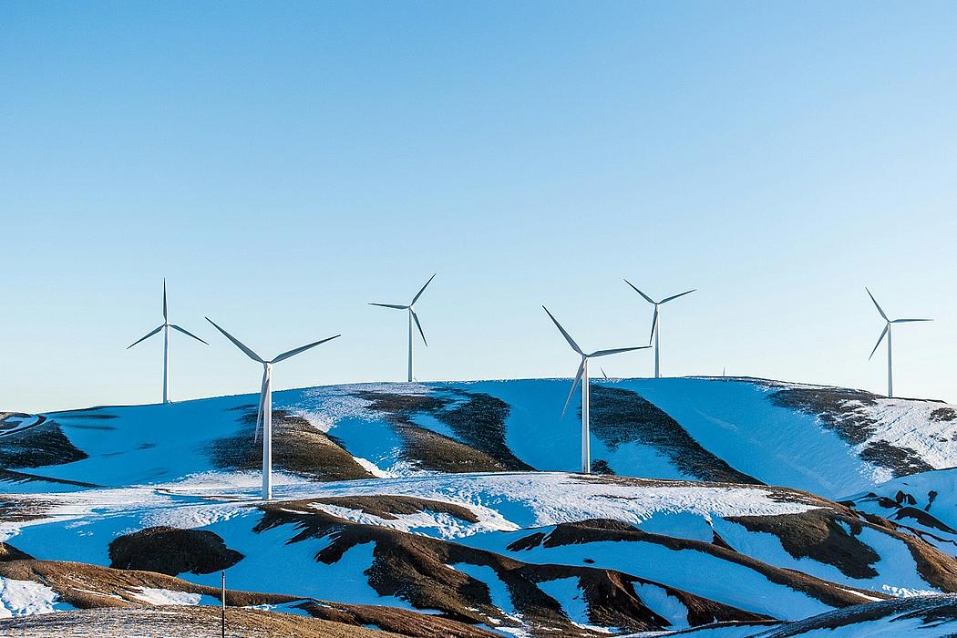 Windenergieanlagen auf einem Berg mit Schneefeldern