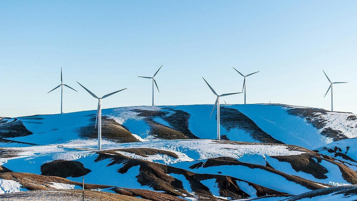 Windenergieanlagen auf einem Berg mit Schneefeldern