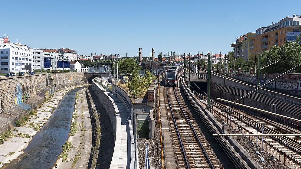 Gerinsel eines Flusses im Betonbett und U-Bahnlinie