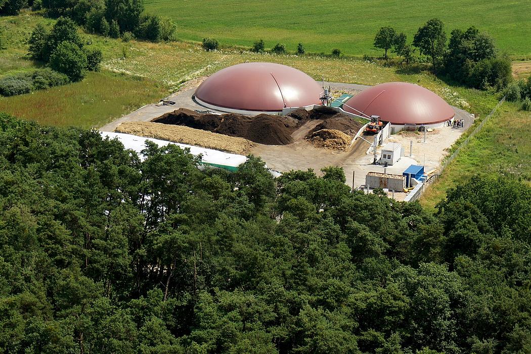 Biogasanlage in einer Landschaft mit Bäumen und Gras