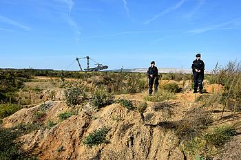 Zwei Polizistinnen stehen auf einem Erdwall zwischen Hambacher Wald und Braunkohletagebau
