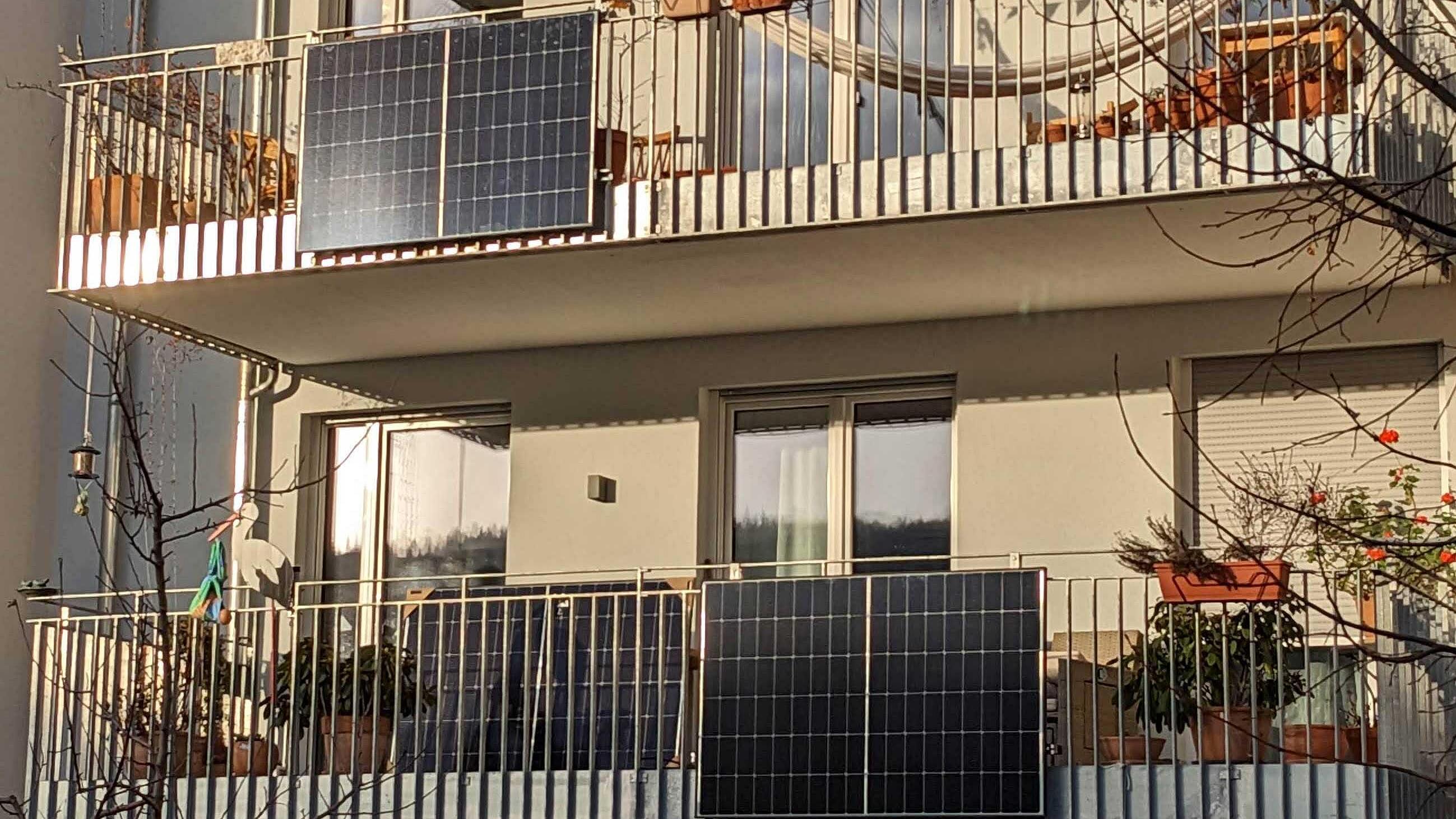 Balkone eines hellen, modernden Gebäudes mit Solarmodulen an Gittern 