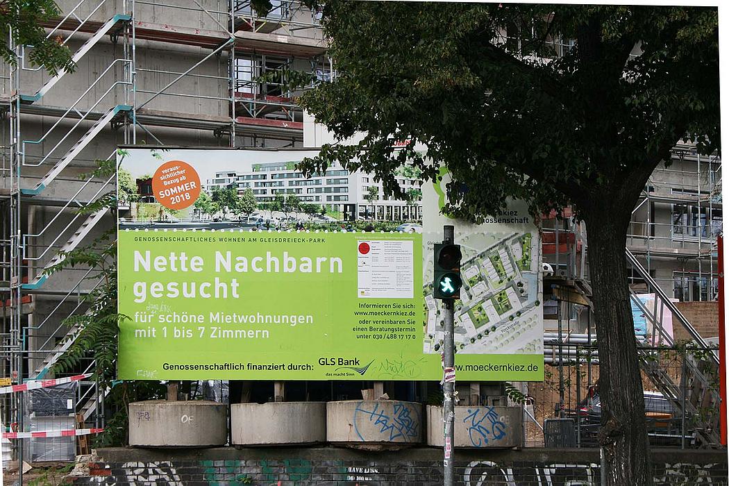 Foto: Schild mit Aufschrift Nette Nachbarn gesucht. Im Hintergrund Haus im Bau.