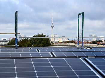Photovoltaikanlage auf einem Dach, im Hintergrund der Fernsehturm am Alexanderplatz in Berlin.
