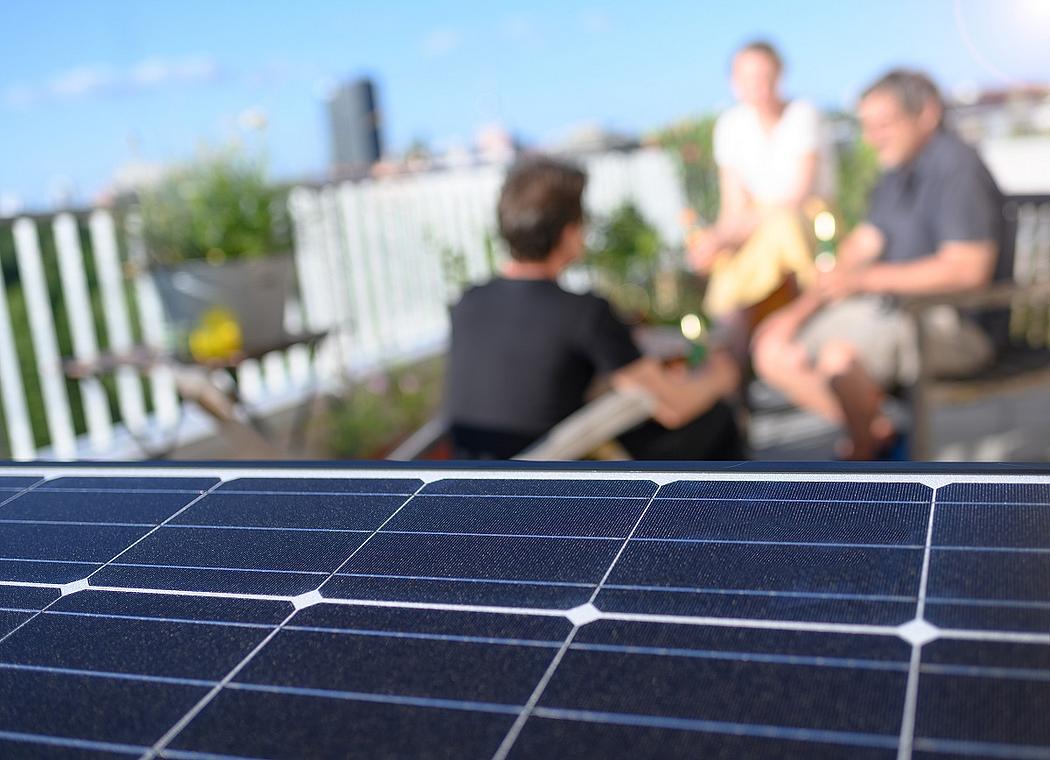 Menschen auf einer Dachterrasse mit Solaranlage auf dem Dach