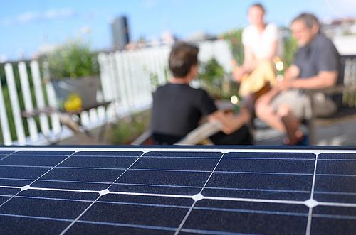 Menschen auf einer Dachterrasse mit Solaranlage auf dem Dach