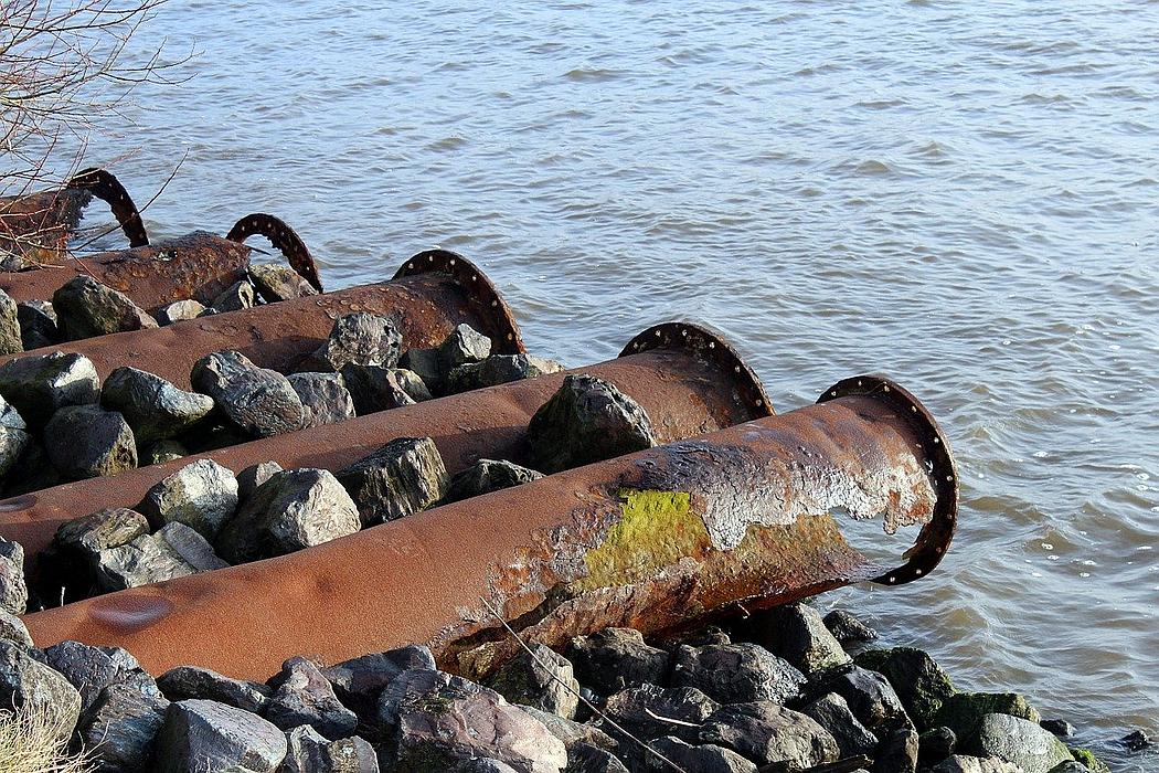 Verrostete Abwasserrohre an einem Fluss