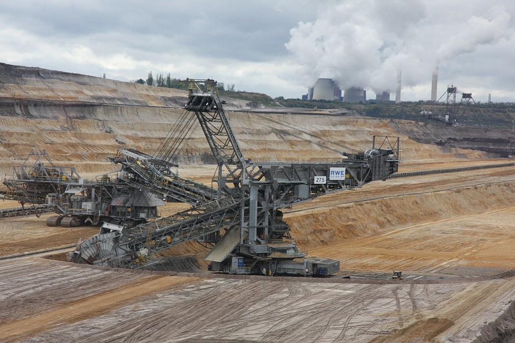 Ein Kohlebagger im Tagebau. Dahinter ein Kohlekraftwerk.