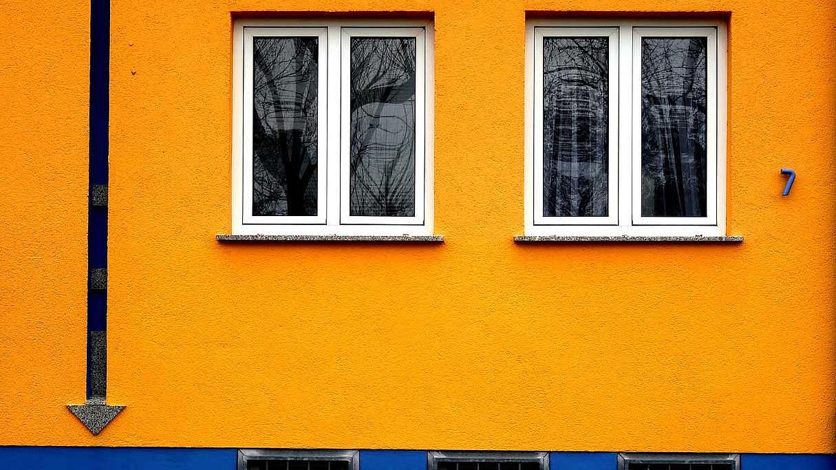 Orange Hausfassade mit zwei Fenstern