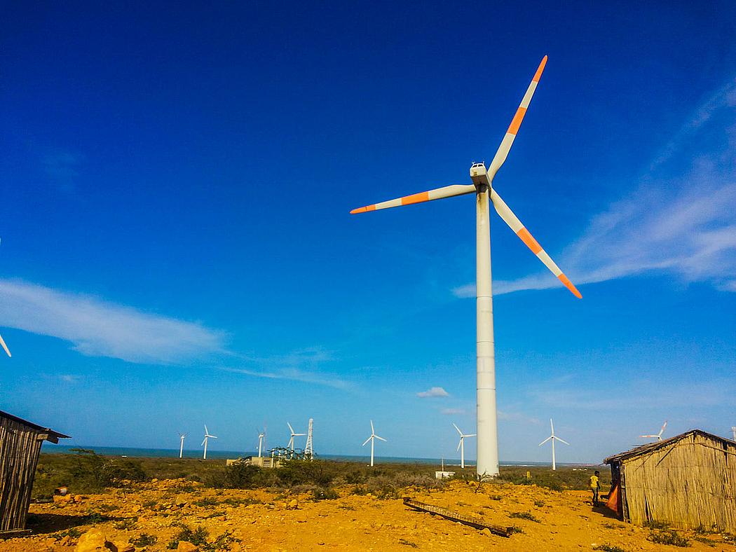 Windräder in einer Wüstenlandschaft mit Holzhütten