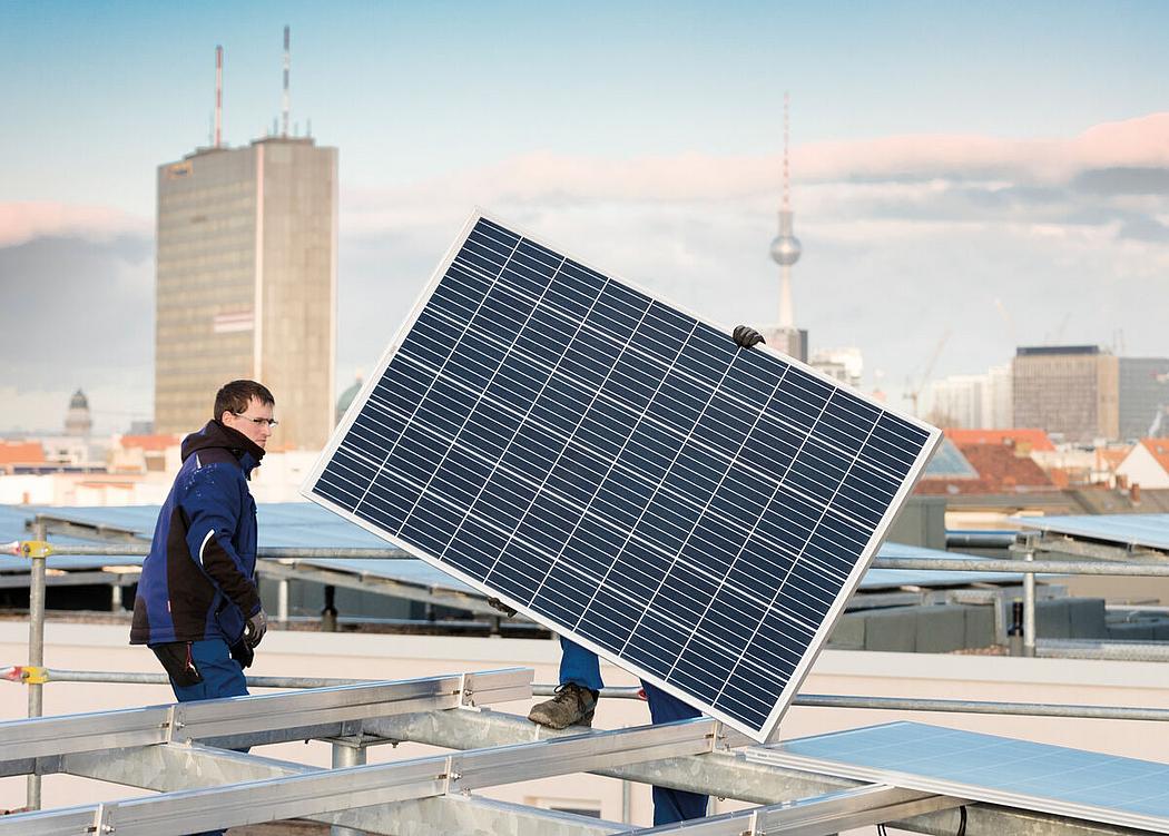 Ein Mann trägt ein Solarmodul auf einem Dach