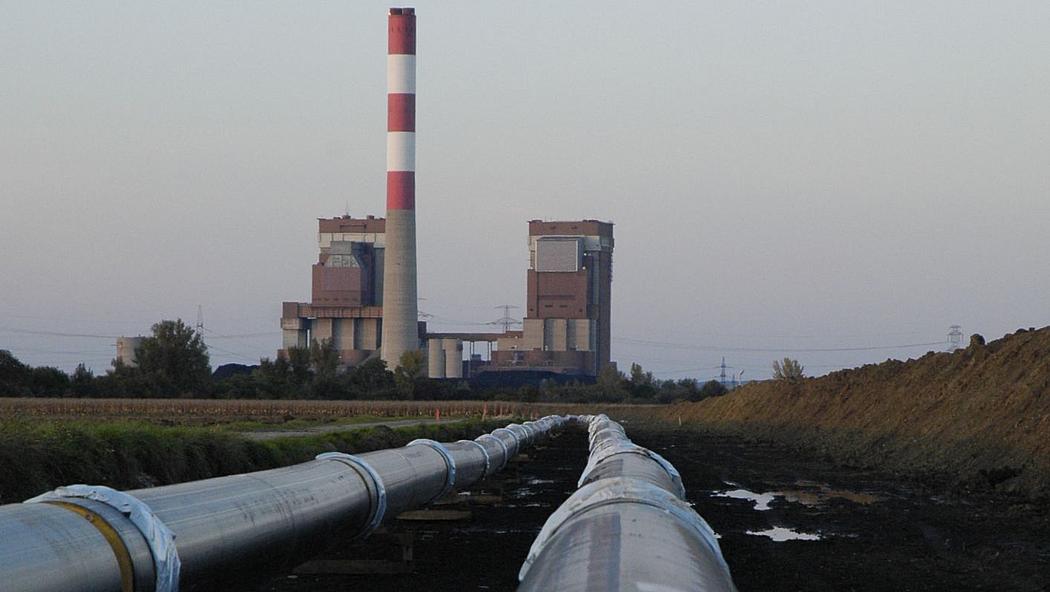 Silberne Leitung am Boden und Kraftwerk im Hintergrund