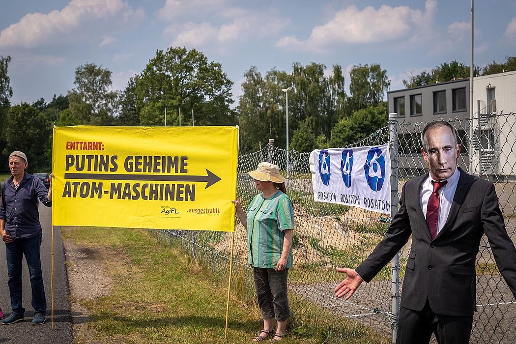 Atomkraftgegner mit einem Plakat „Putins geheime Atom-Maschinen“ daneben ein Mensch mit Putin-Maske
