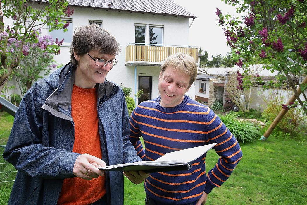 Zwei Männer im Gespräch vor einem Einfamilienhaus