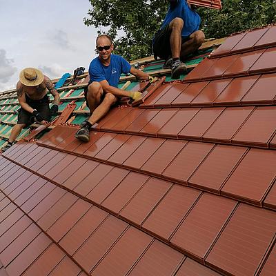 Dachdecker verlegen terrakottafarbene solare Dachziegel