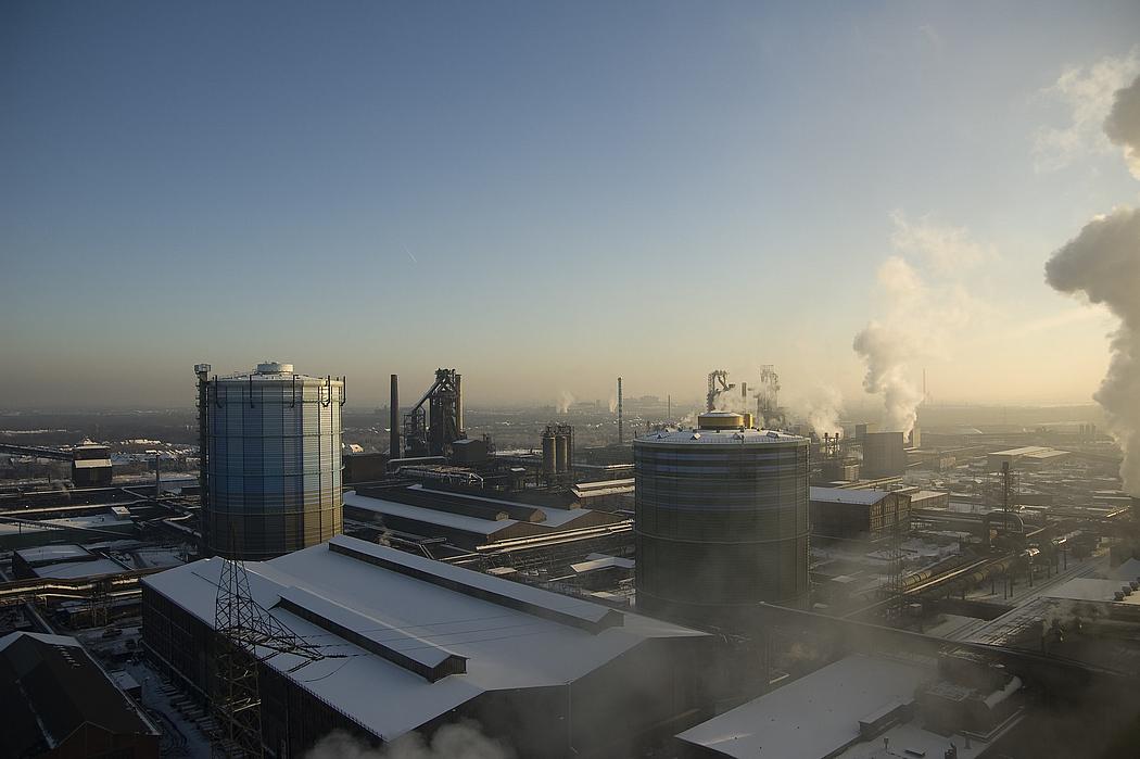 Industrieareal mit rauchenden Schornsteinen im Winter bei Schnee