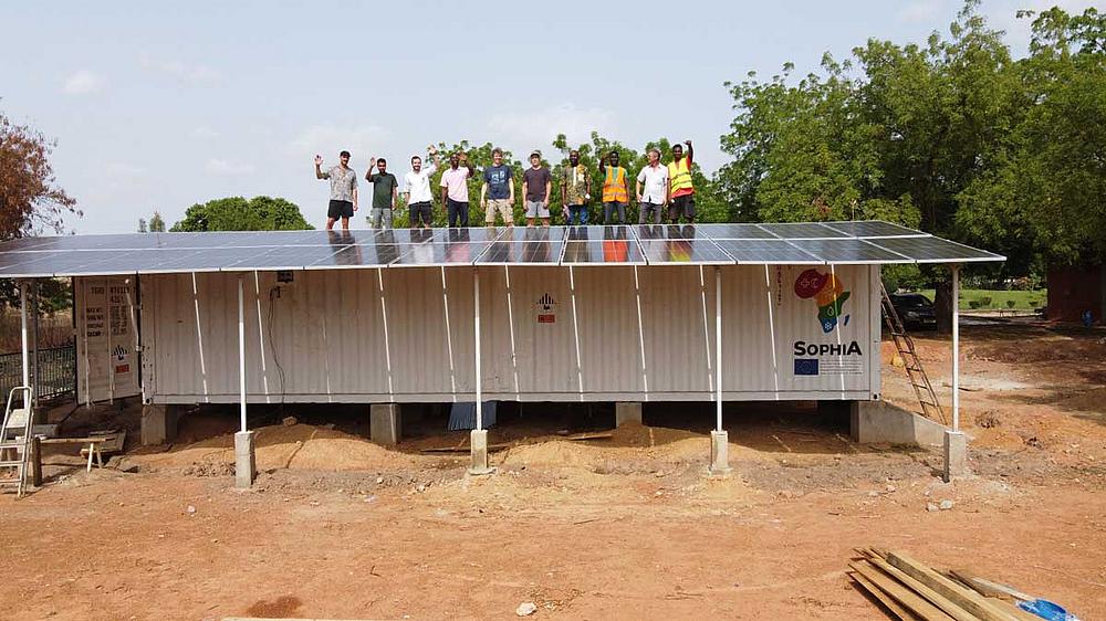 Mehrere Personen auf Container mit PV-Modulen