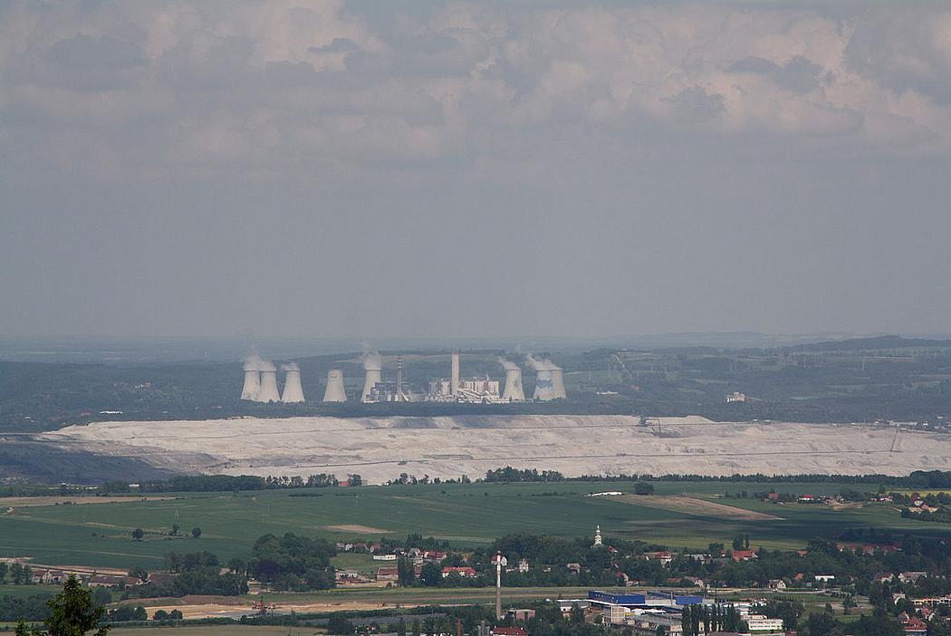 Im Vordergrund eine Stadt, dahinter der Tagebau Turów und im Hintergrund ein Kohlekraftwerk