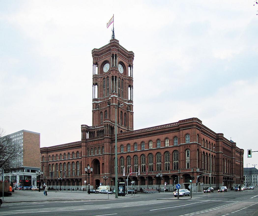 ein langgezogenes rotes Gebäude mit Turm und Uhr