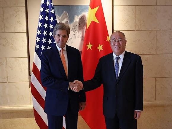 Zwei Männer in Anzug vor einer US-amerikanischen und chinesischen Flagge