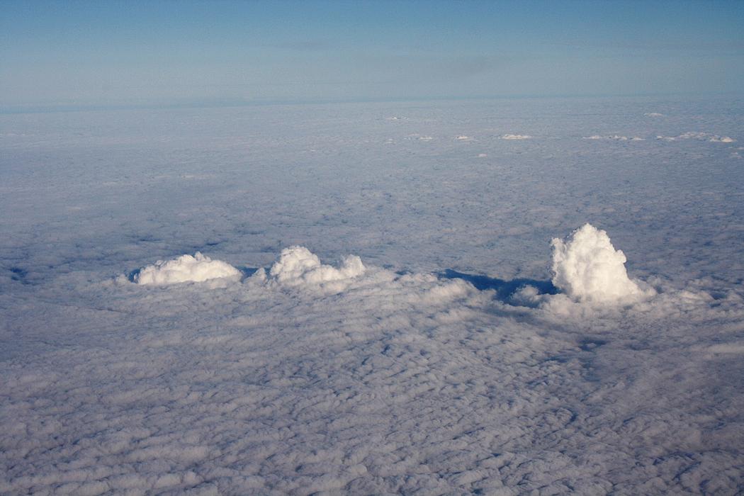 Dampfwolken der Braunkohlekraftwerke Frimmersdorf (links), Neurath (Mitte) und Niederaußem (rechts) aus Wasserdampf und CO2 durchstoßen die Wolkenschicht. (Foto: © <a href="https://de.wikipedia.org/wiki/Datei:FrimmersdorfWolke7.JPG">Arne Hückelheim</a>, <a href="https://creativecommons.org/licenses/by-sa/4.0/" target="_blank">CC BY-SA 4.0</a>)