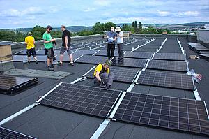 Menschen arbeiten auf einem Flachdach an einer Solaranlage