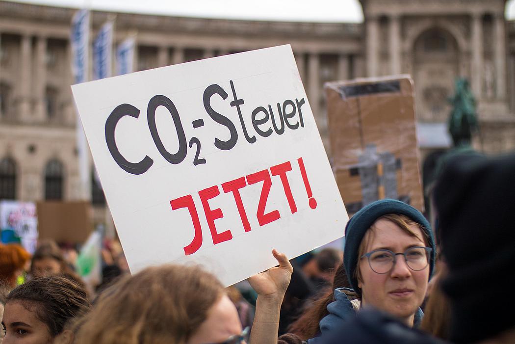 Demonstrantin bei einer Demo von Fridays for Future mit einem Plakat auf dem steht: "CO2-Steuer jetzt!"
