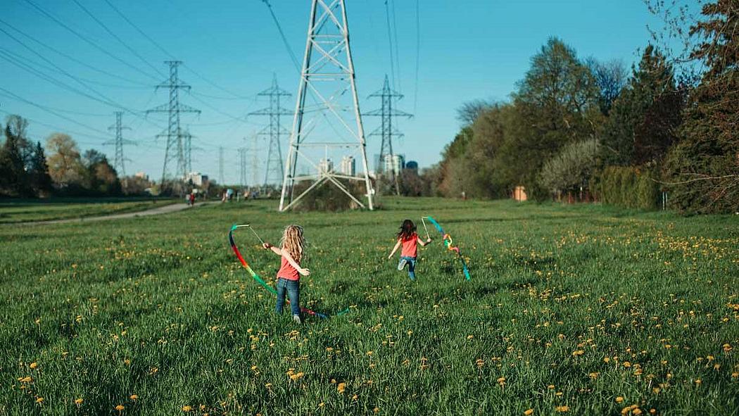 Kinder auf einer Wiese unter Strommast