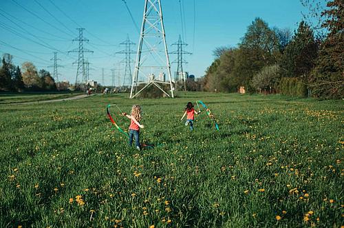 Kinder auf einer Wiese unter Strommast