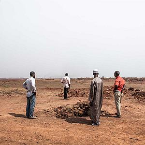 Menschengruppe in weiter öder Landschaft in Guinea