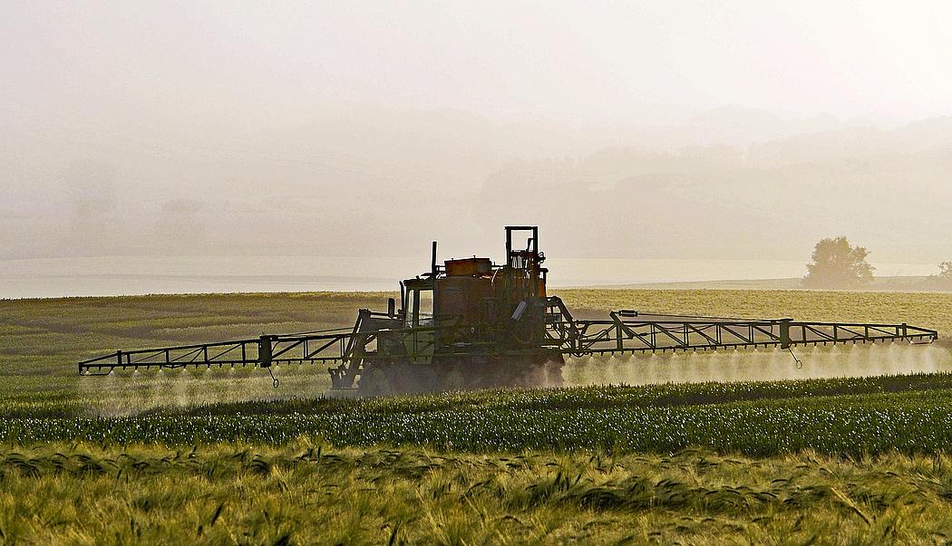 Traktor bringt Pestizide auf Acker aus
