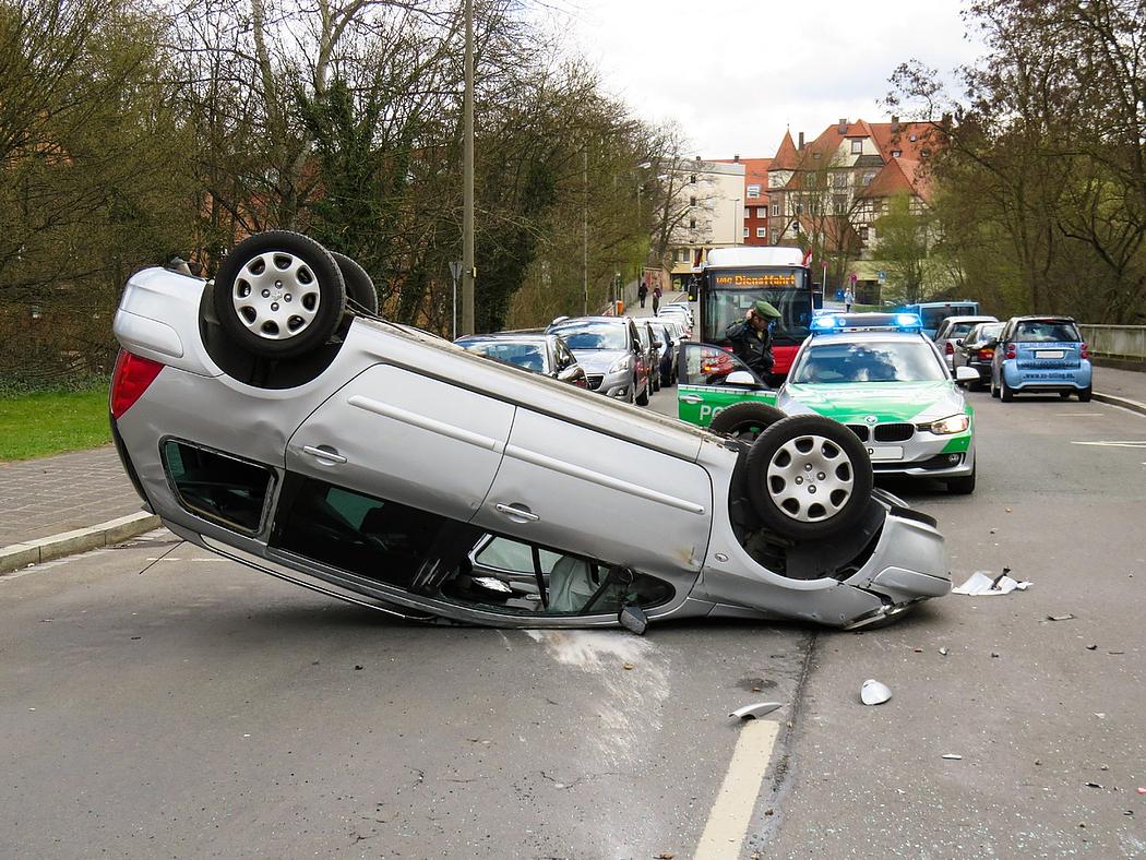 Ein silberner Pkw steht nach einem Unfall auf dem Kopf