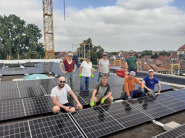 Acht Männer und Frauen auf einem Flachdach mit Solaranlage