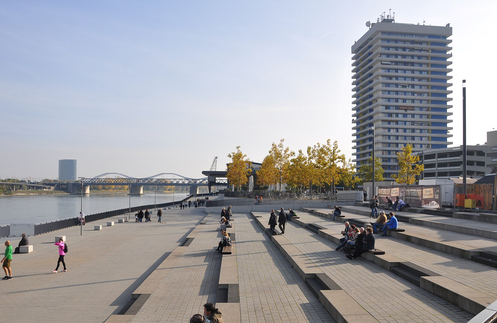 Betontreppe am Ufer eines Flusses, mit Hochhaus im Hintergrund