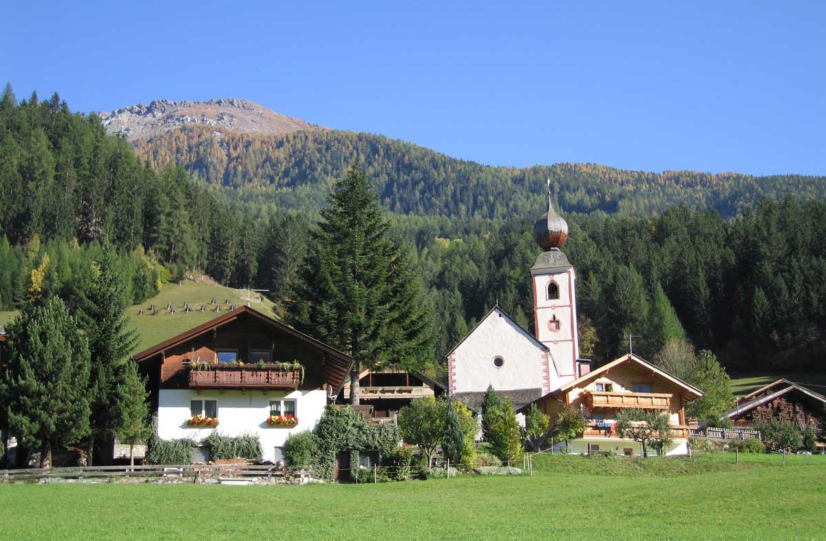 Privathäuser in Kärnten, kleine Kirche im Hintergrund Berg