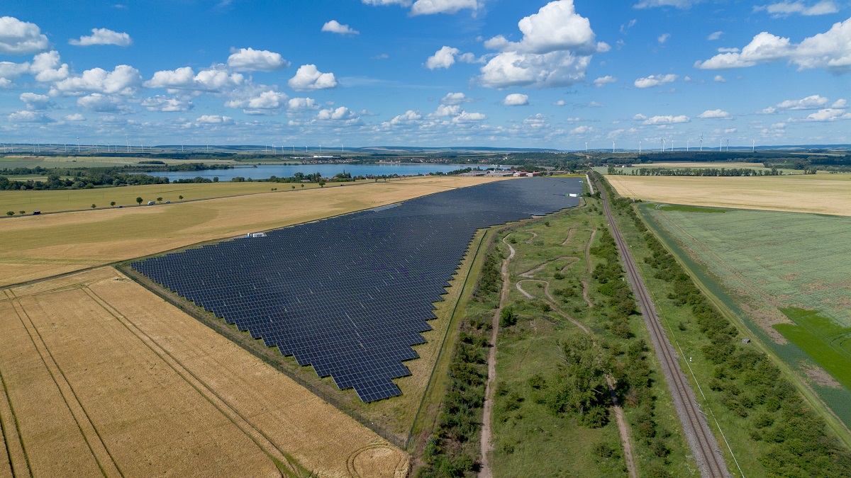 Blick auf großen Solarpark und Grünflächen, im Hintergrund ein See